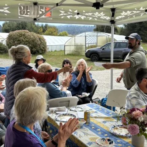 A group of people under an awning, clapping.