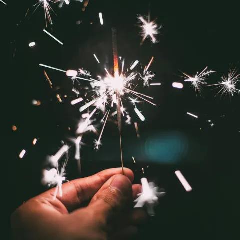 Hand holding sparkler firework at night