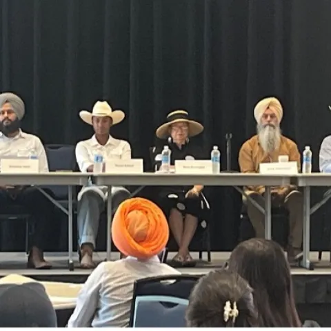 Seven farmers sitting at a long table on stage facing the audience