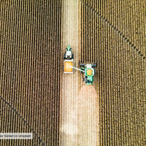 Aerial view of harvester driving through crop field 