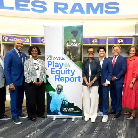Hannah Thompson, in red dress, with legislators, advocates and experts at a special session of the CA Senate Education Committee at SoFi Stadium