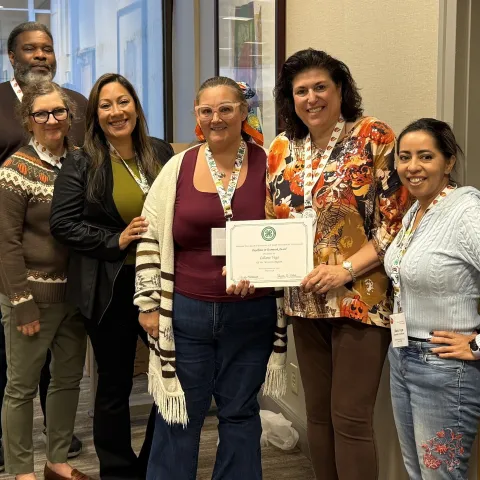 6 people pose with a certificate held by one person