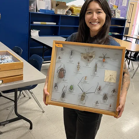 Mia holds glass case displaying bugs