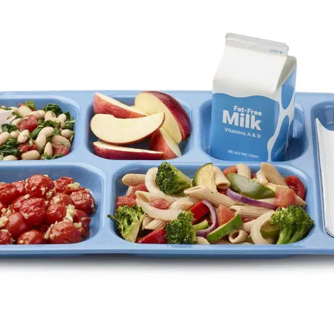 A tray of school food including fresh fruits, vegetables, milk and an entree.