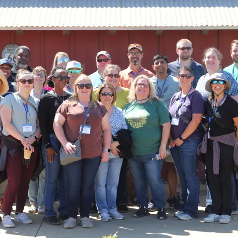 A group of people pose for a photo in several rows during a farm tour