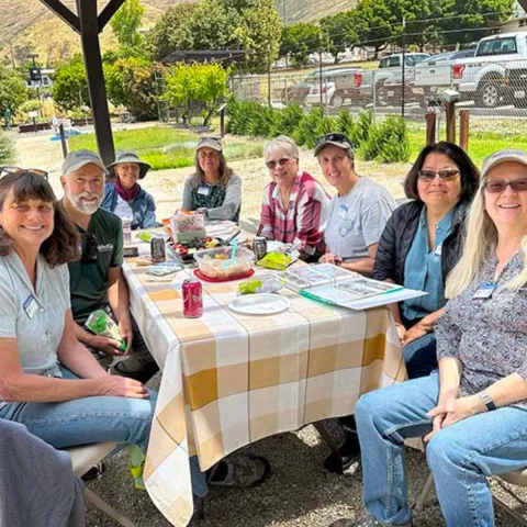 a group of volunteers sitting around a lunch table discussing garden things 