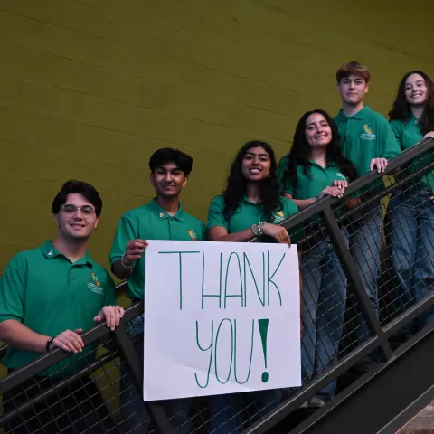 2025-26 State Ambassadors hold a large Thank You sign while standing on the stairs inside ANR building.