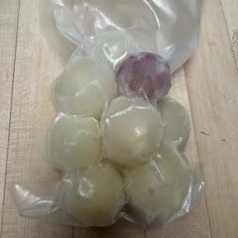 A freezer bag full of small, frozen onions.