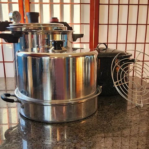 Pressure, steam, and water bath canners with a rack on a dark, granite counter.