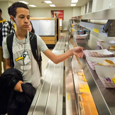 Image of a young adult grabbing breakfast from the school cafeteria.