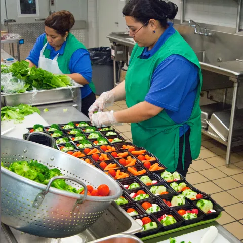 Food service staff preparing healthy school meals in a school kitchen.
