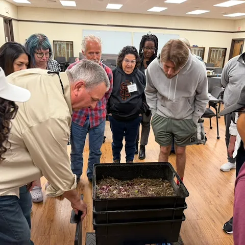 Randy Thomson showing his composting with worms bin to a group of adult workshop attendees