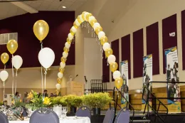 Yellow and white balloon arch and UCCE banners as decor at the centennial celebration.