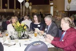 UCCE and community members seated and reading a pamphlet