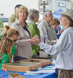 Visitors queue at a garden market help desk, interacting with a Master Gardener.