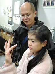 Lynn Chang of Redwood City watches his daughter. Joy, handle a stick insect. (Photo by Kathy Keatley Garvey)