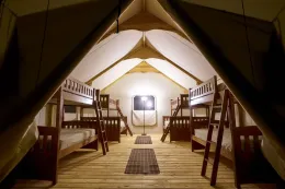 Interior of canvas tent with several sets of bunk beds.