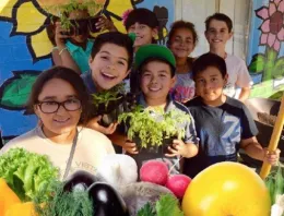 Picture of boys and girls holding up vegetables they grew