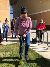 Woman pressing a 4'soil probe into a lawn.