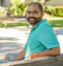 Author sitting on park bench wearing green shirt and smiling.