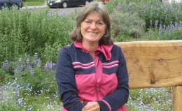 Author sitting on bench with a background of wildflowers.