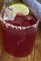 Glass with red liquid, ice, and salt around the rim.