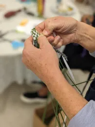 Hands of a Master Gardener wrapping ribbon around lavender stems.