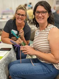Two women smiling holding several lavender wands.