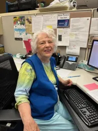 Author sitting at a desk, wearing a blue vest, smiling.
