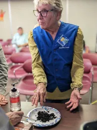 Woman standing at table with a plate of soil and worms.