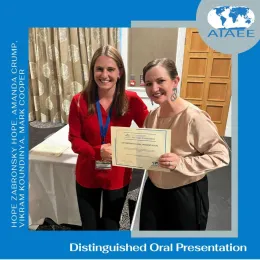 Hope Zabronsky wearing a red top accepts an award certificate from a woman.