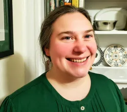 Kirsten H smiles and wears a dark green blouse.