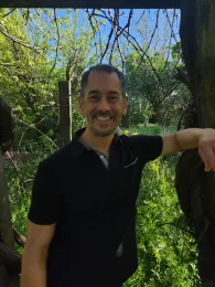black-haired male in black shirt with verdant background