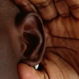 Person listening with their hand cupped behind their ear