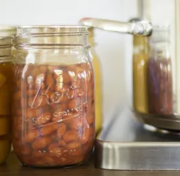 Jars of pinto beans next to canner on a burner. 