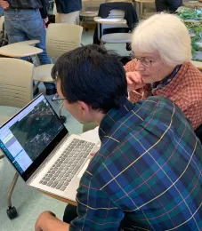 A man and a woman work in front of a computer.