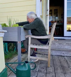 Wowan sitting in a chair working in a raised bed garden