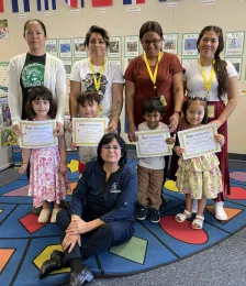 Four mothers with their young children displaying the graduation certificates they earned in EFNEP classes.