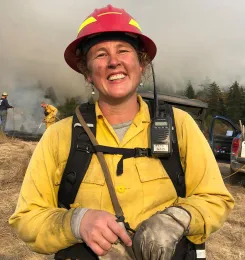 Woman wearing a red hard hat, yellow protective jacket and a glove on her left hand