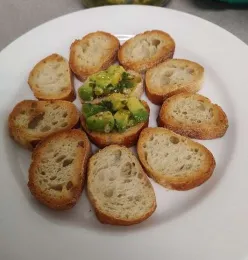 avocado bruschetta topped crostini on a white dish
