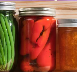 glass jars containing shelf-stable green beans, tomatoes, and marmalade
