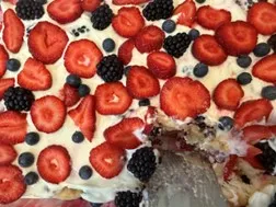 Tiramisu with sliced strawberries, blueberries and blackberries on top