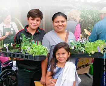 A family purchases vegetable starts for the garden from the farmers market.