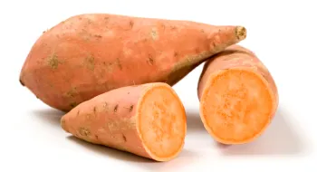 two orange sweet potatoes, one cut open to show the orange interior flesh