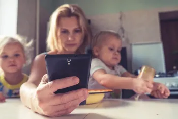 Woman on a smartphone while caring for children