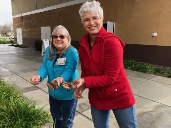 Two women holding soil samples and smiling.