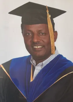 Man posing in his graduation gown.