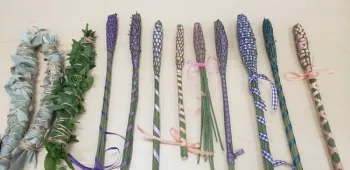 Nine wands of various colors (purple, pink, lavender) on display on a table.