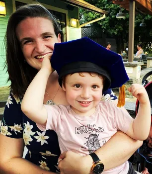 Griffin Alberts, 3, shown here with his mother, Charlotte Herbert Alberts, a new PhD, tries on