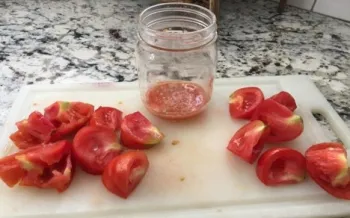 Cherry tomatoes, a cutting board, and a mason jar on a counter.